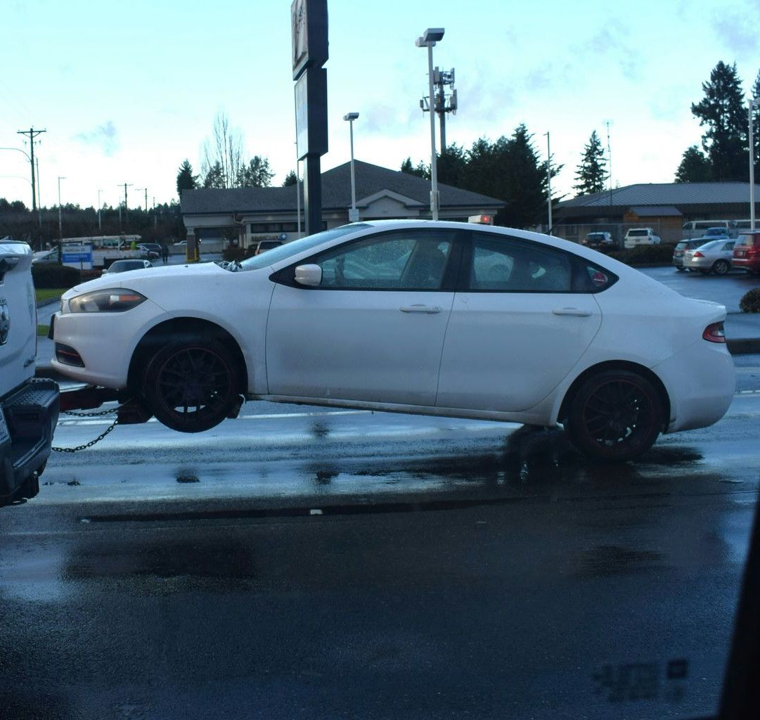 a white car being towed by a tow truck